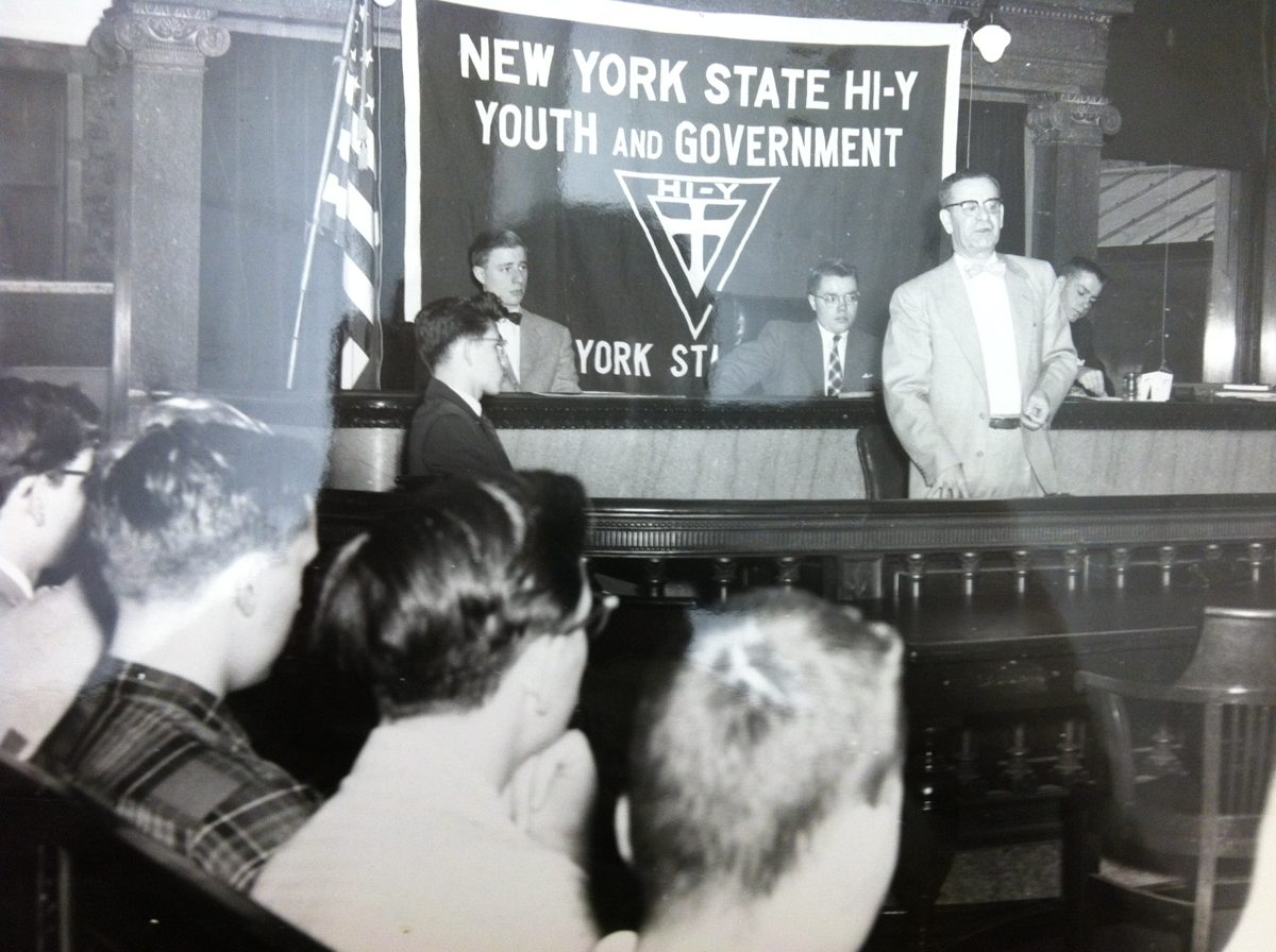 Clement Duran addressing delegates beneath a New York State Hi-Y Youth and Government banner