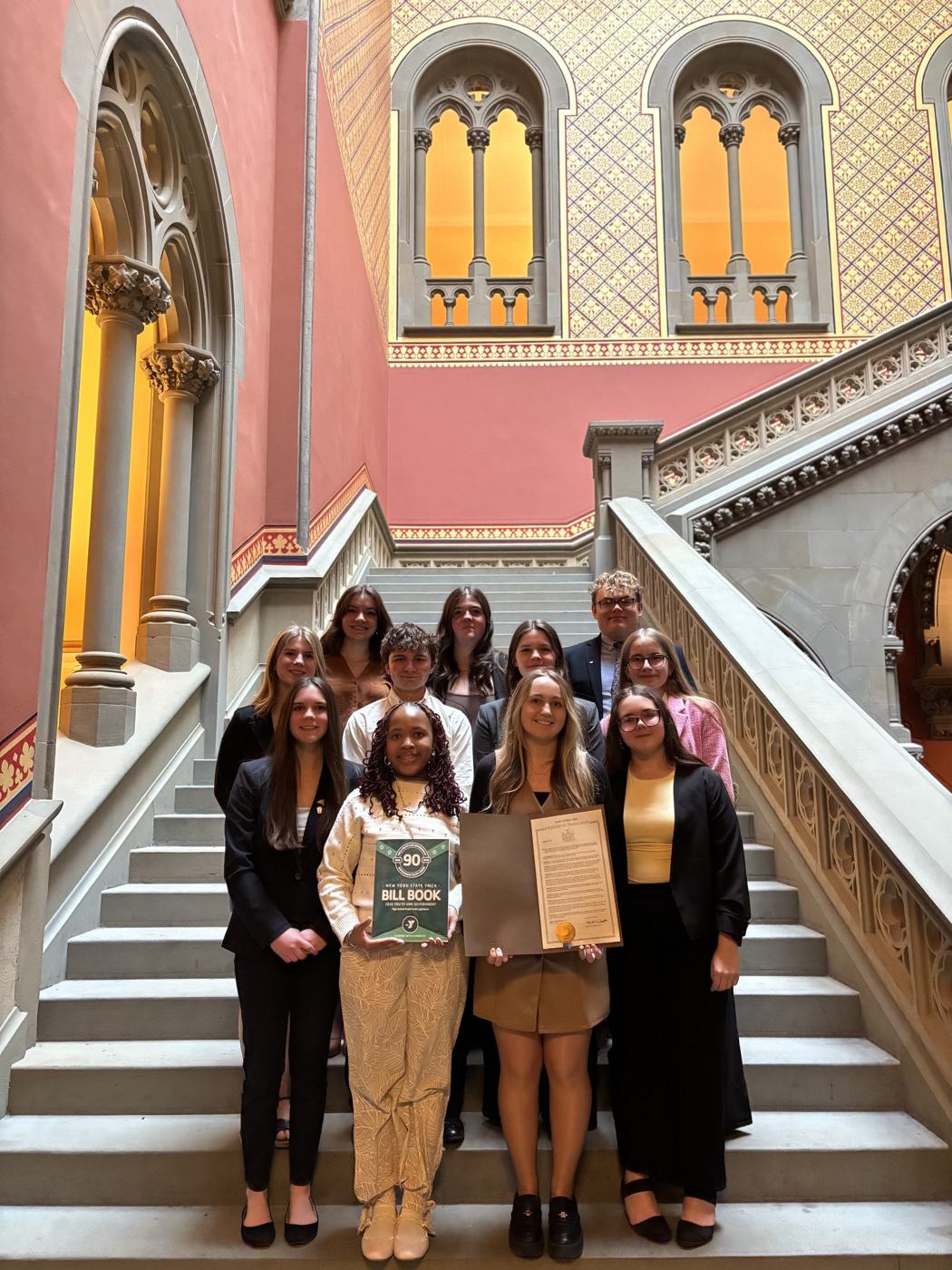 New York delegates on the Capitol staircase holding the Bill Book